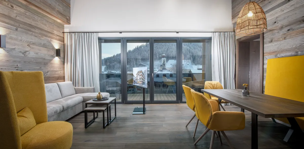 Helles, modernes Wohnzimmer im Appartement mit Essbereich und gelben Stühlen vor großer Fensterfront