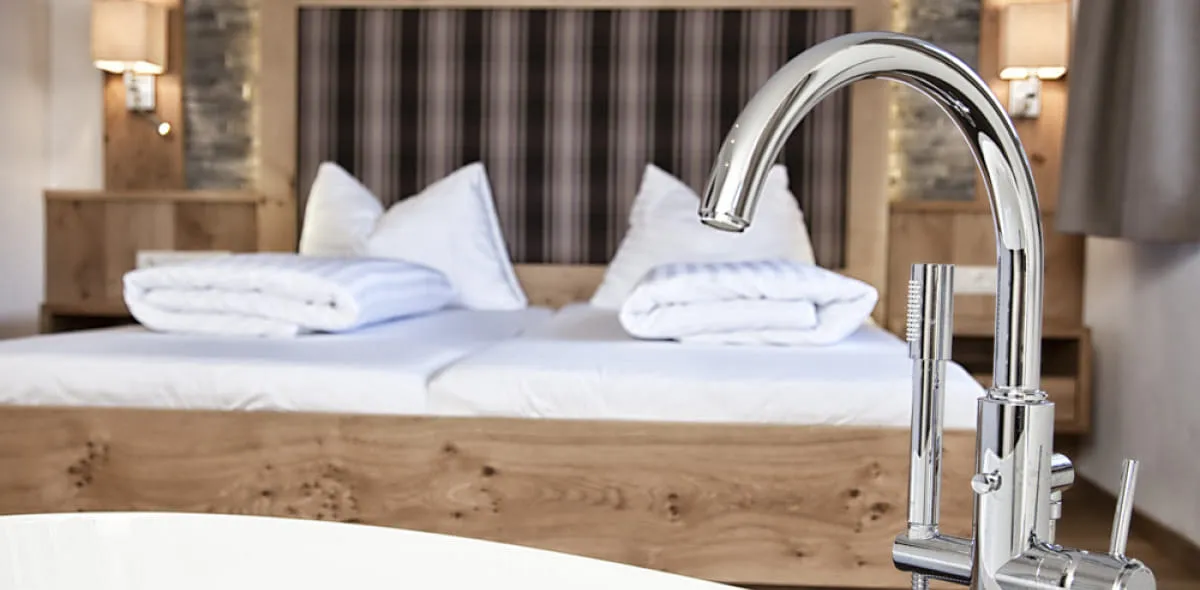 Schlafzimmer mit Doppelbett hinter Badewanne