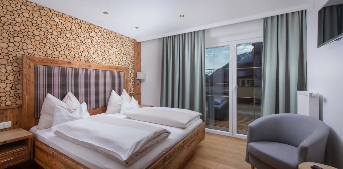 Großzügiges Schlafzimmer mit Doppelbett und Polstersessel