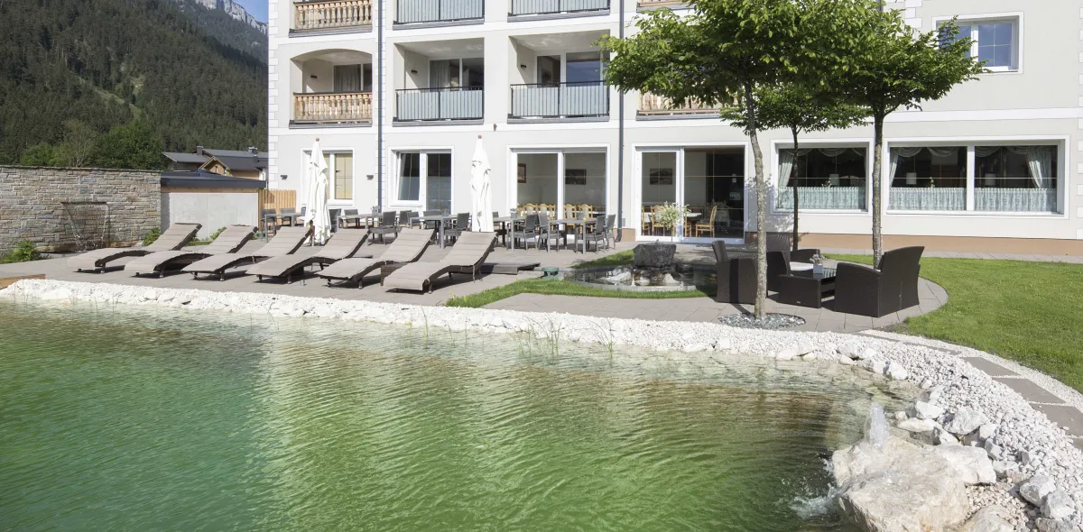 Sonnenterrasse mit Liegen und Sitzbereich neben Schwimmteich