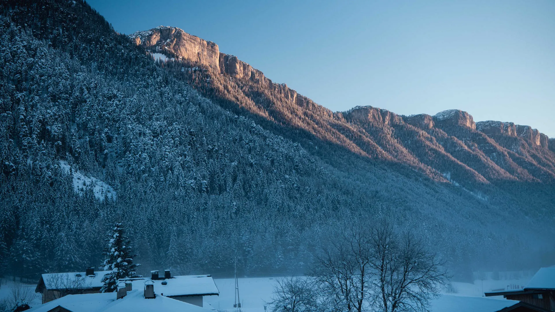 Verschneite Winterlandschaft vor Bergkulisse im Sonnenuntergang