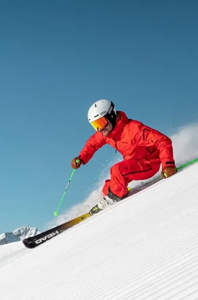 Skifahrer in rotem Skianzug bei sportlicher Abfahrt